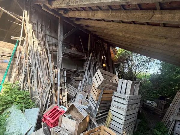 Mit Holzkisten vollgestellter Schuppen vor der Räumung