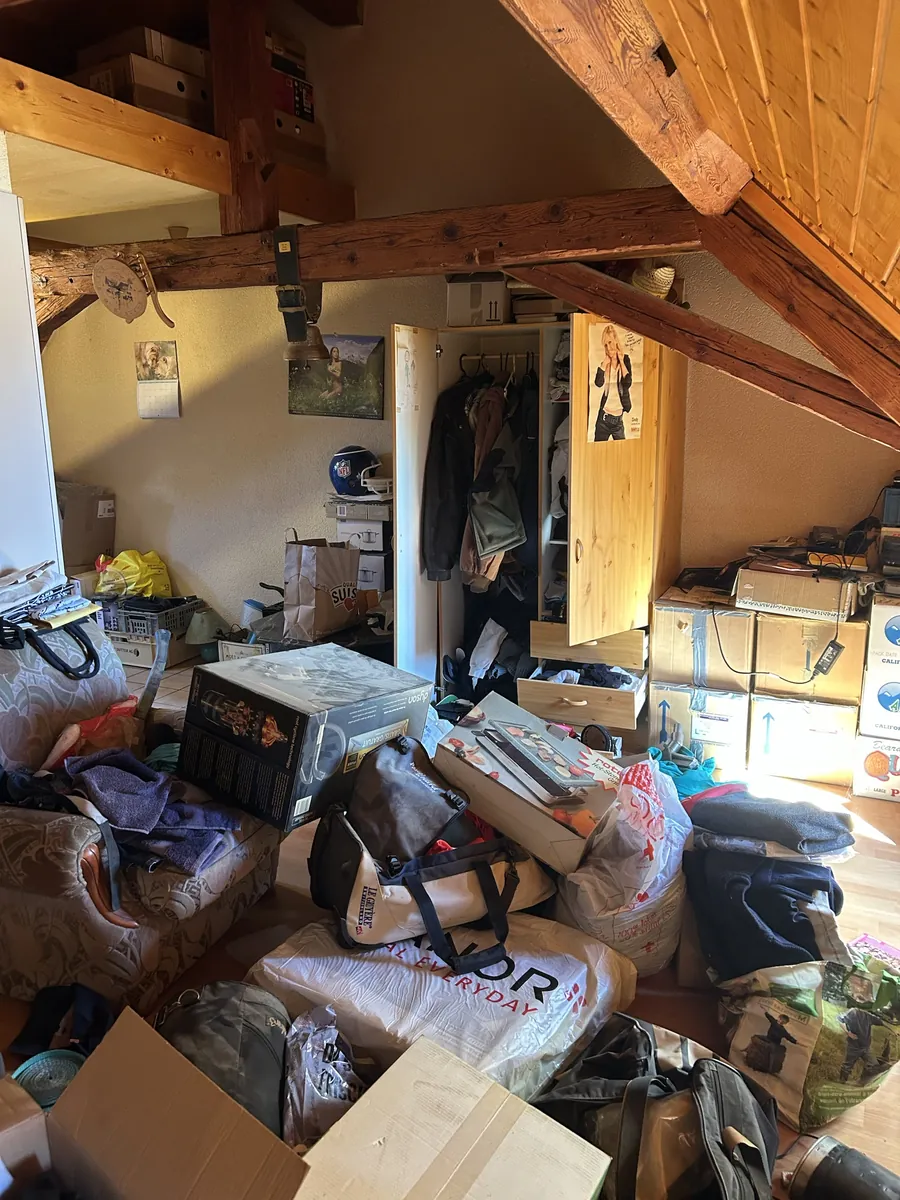 Combles d'appartement encombrés de cartons, sacs et mobilier avant un débarras à Fribourg