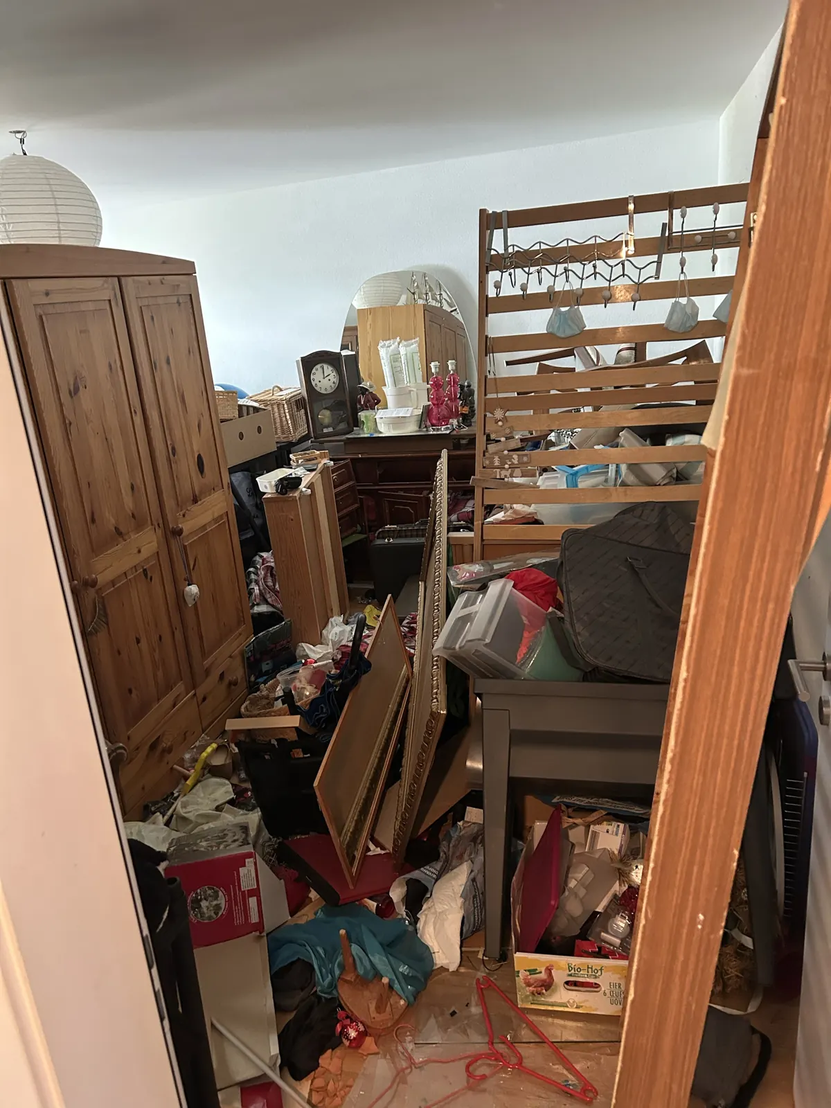 Chambre encombrée de meubles, cartons et objets avant un débarras à Fribourg