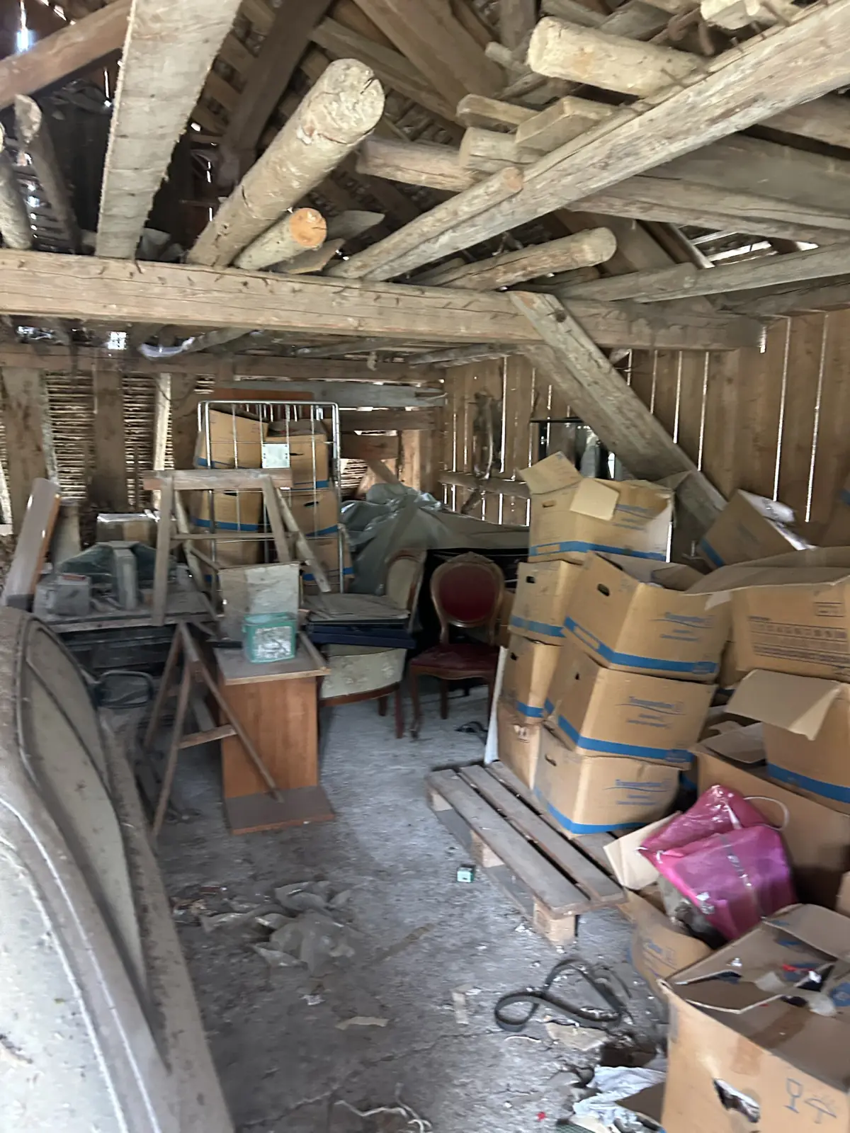Grange et remise sous charpente remplies de cartons et vieux meubles avant débarras, région de Fribourg